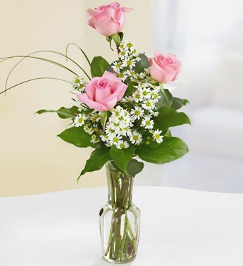 three pink roses in a bud vase with fillers