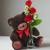 Three red rose in a bud vase with a teddy bear on the side