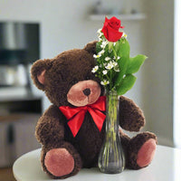 Single red rose in a bud vase with a teddy bear on the side